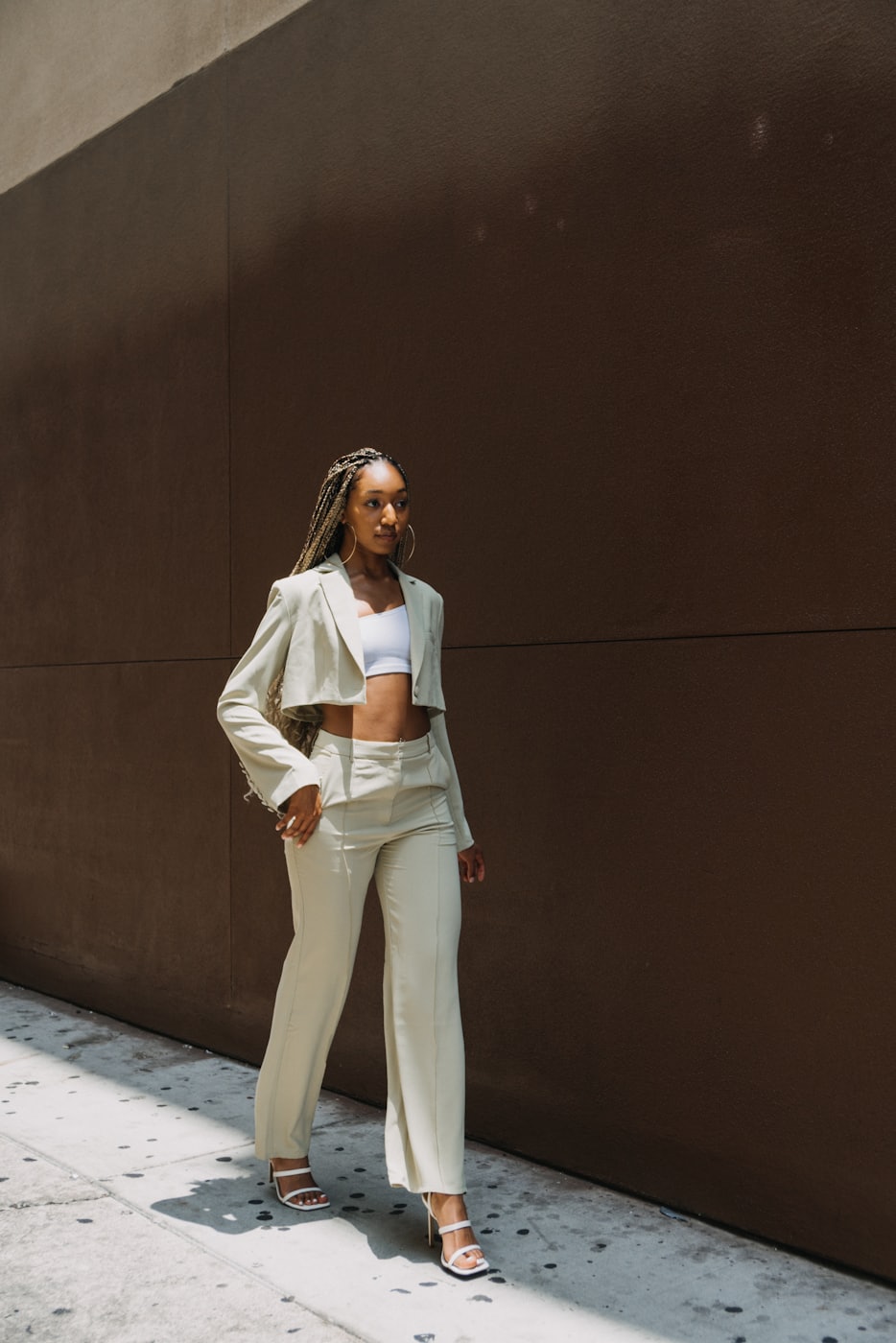 A woman in a cream suit against a deep brown wall